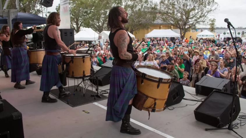 Performers on stage looking out at audience in chairs on lawn