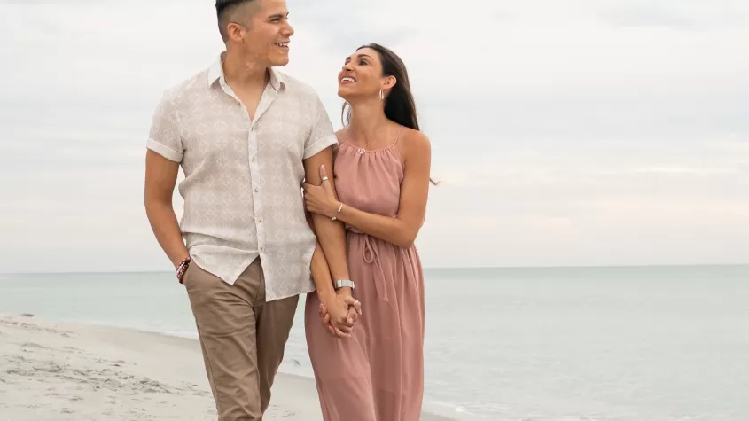 Couple walking alongside the beach laughing