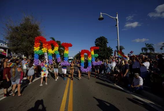 A candid shot of a local Pride parade featuring rainbow colors and marching bands